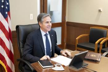 Ο Υπουργός Εξωτερικών των ΗΠΑ, Anthony Blinken, κάθεται σε ένα γραφείο με φόντο την αμερικανική σημαία.